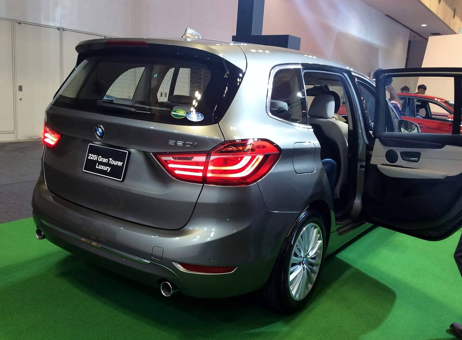Grey BMW 220i Gran Tourer Luxury at a motor show, rear three-quarter view