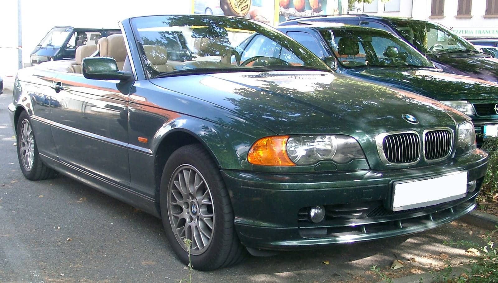 Green BMW 3 Series convertible with the top down, front three-quarter view