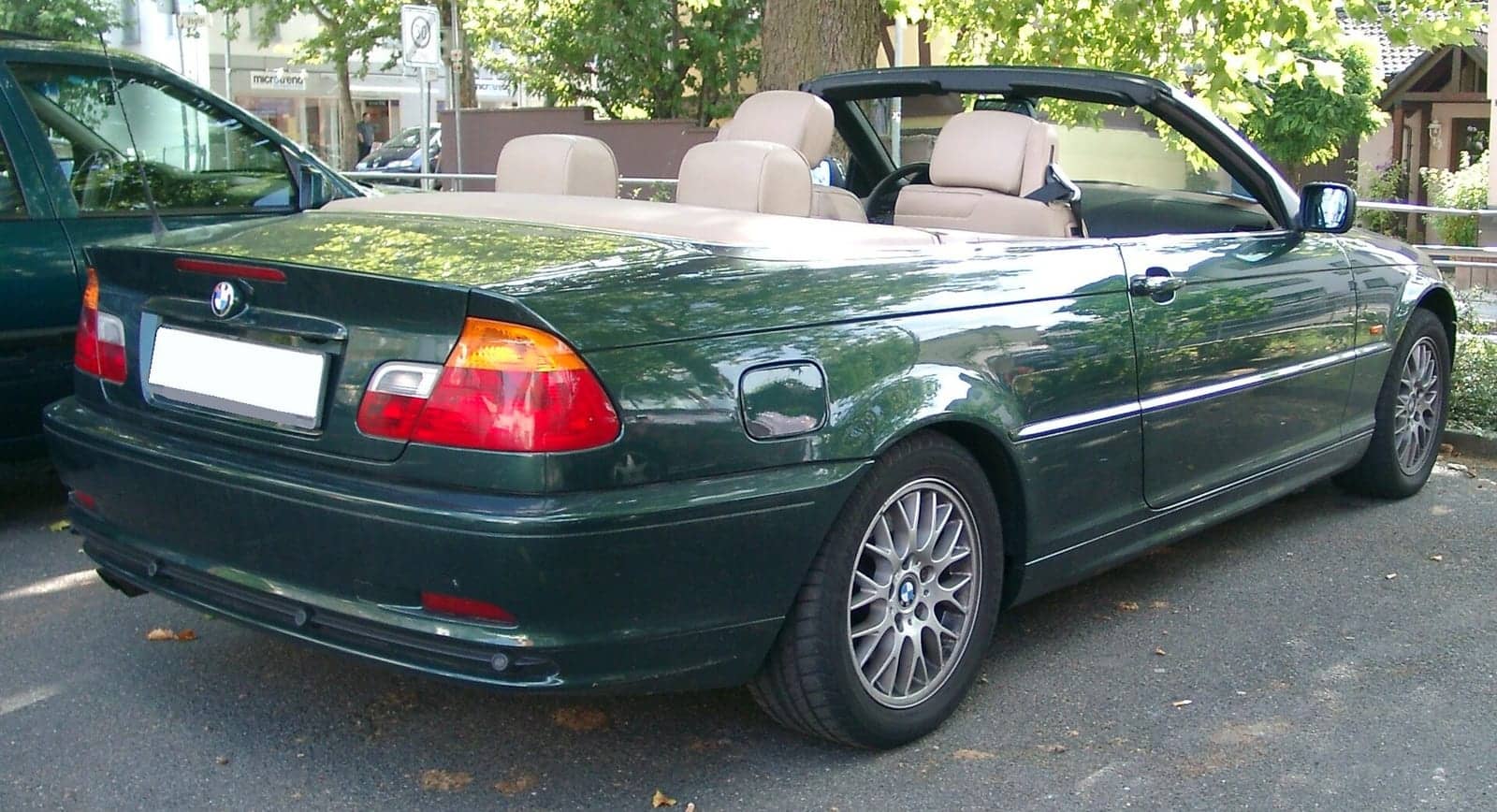 Green BMW 3 Series convertible with the top down, rear three-quarter view