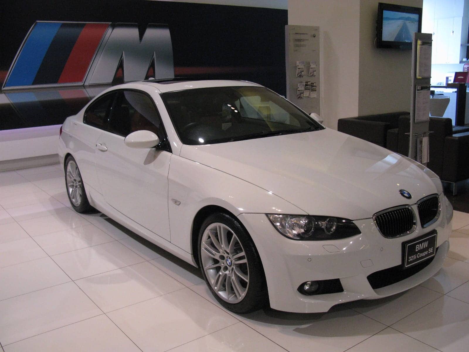White BMW 325i M Sport coupé in a showroom, front three-quarter view