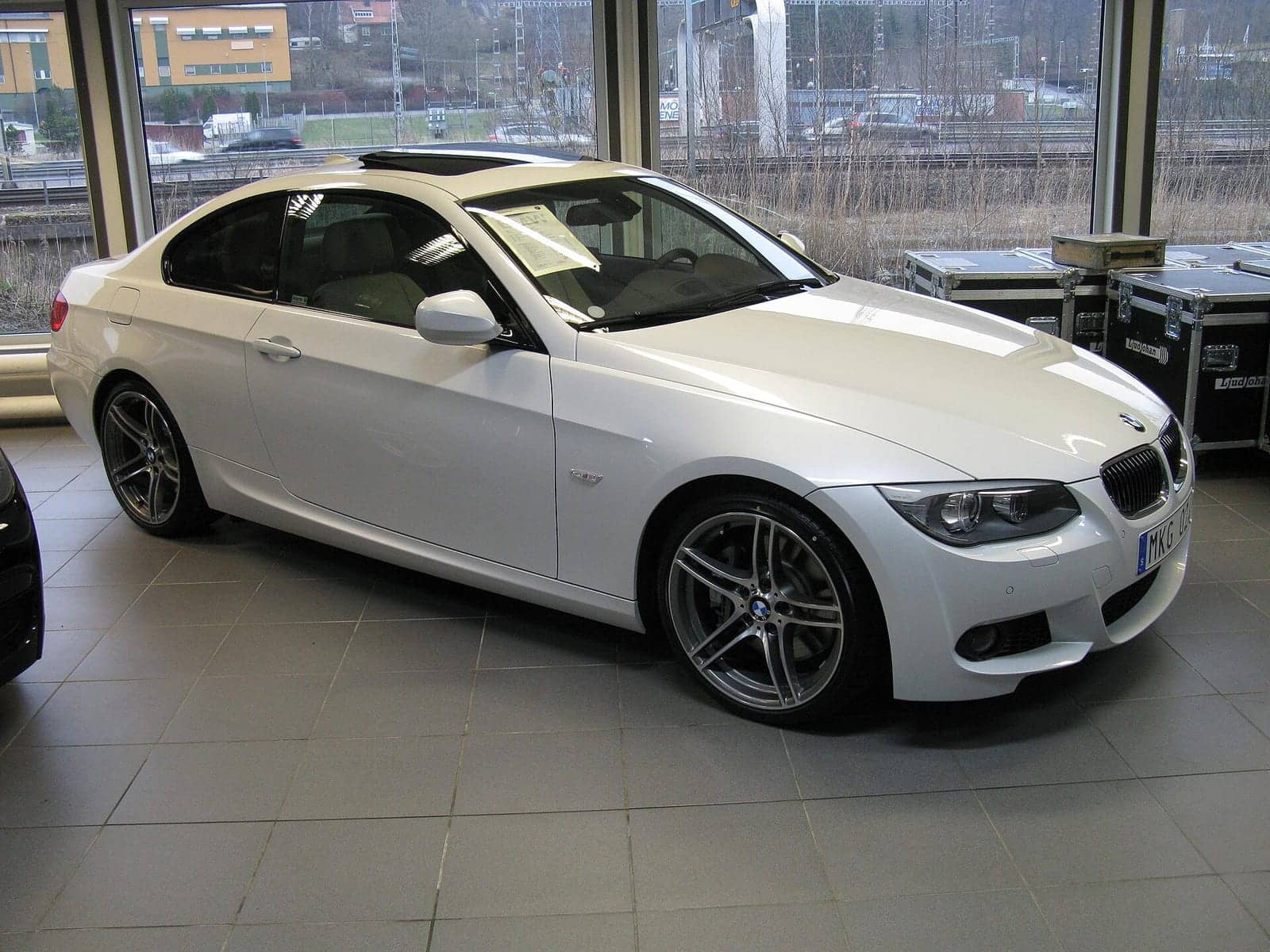 White BMW 335i M Sport coupé in a showroom, front three-quarter view