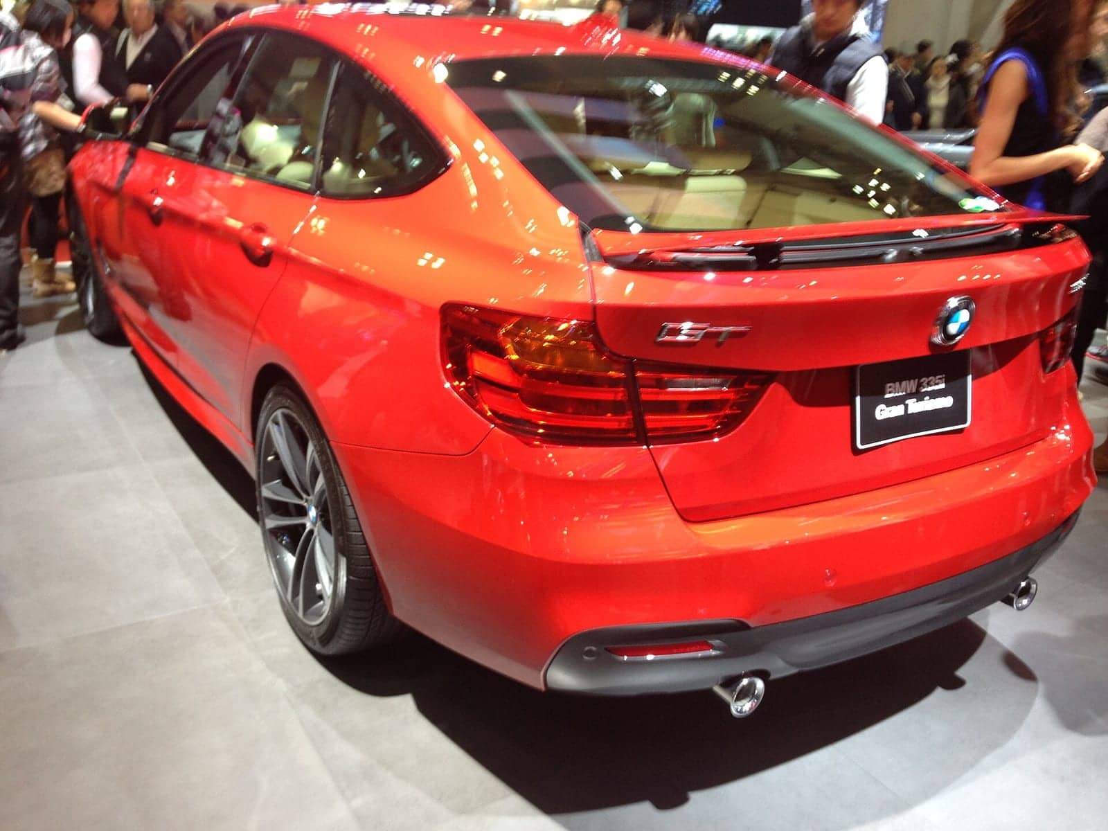 Red BMW 335i Gran Turismo at a motor show, rear three-quarter view