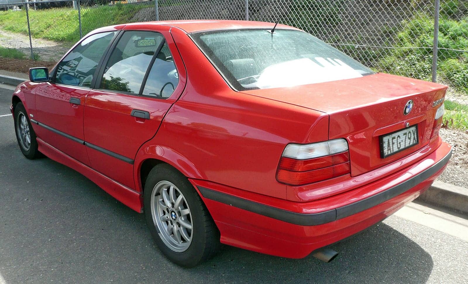 Red BMW 323i sedan, rear three-quarter view