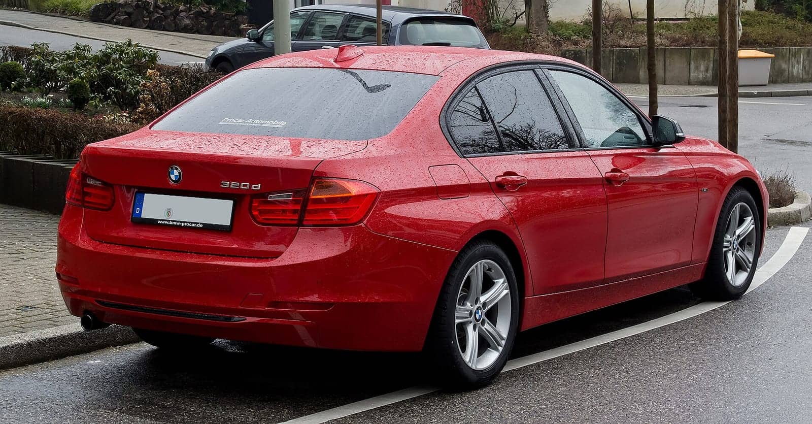 Red BMW 320d Sport Line sedan, rear three-quarter view