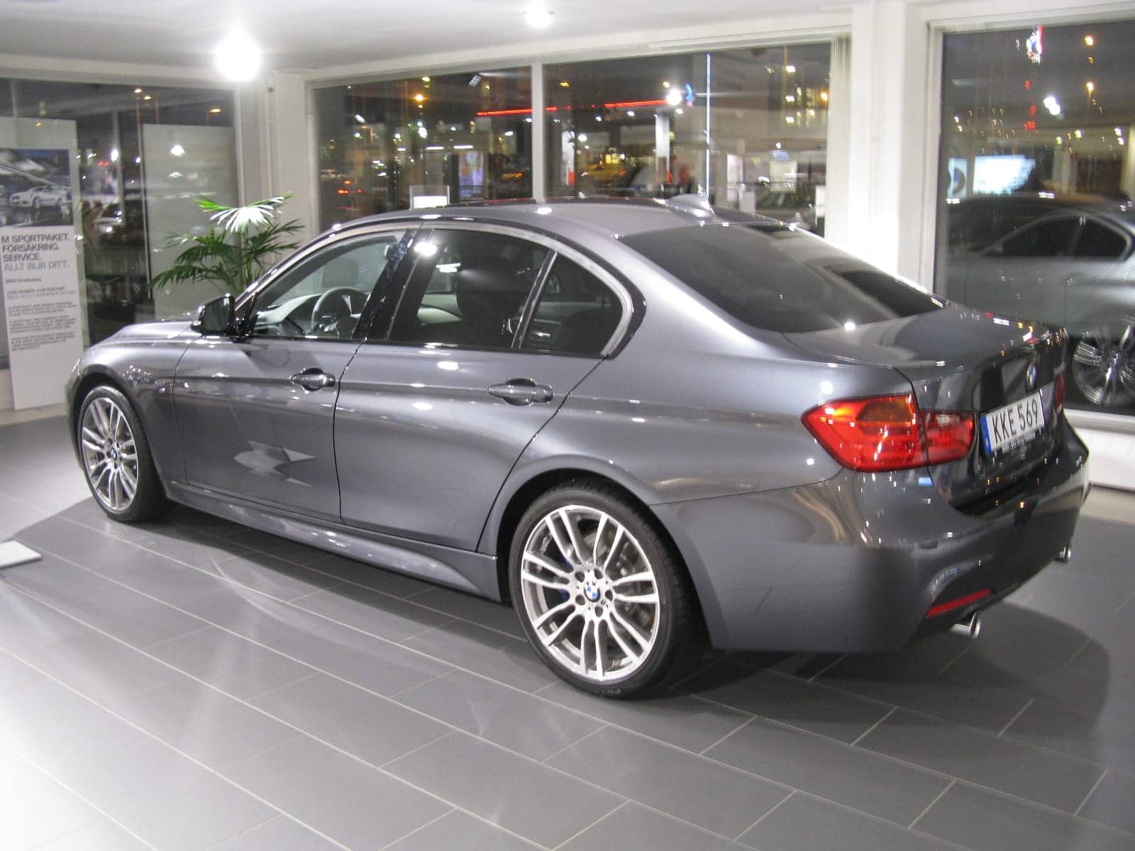 Grey BMW 335i M Sport sedan in a showroom, rear three-quarter view