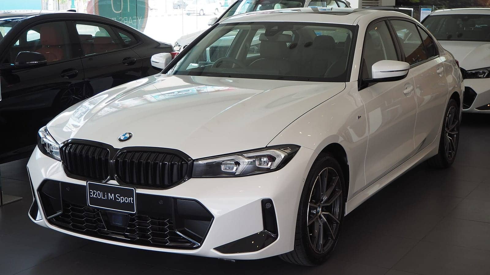 White BMW 320Li M Sport (facelift) in a showroom, front three-quarter view