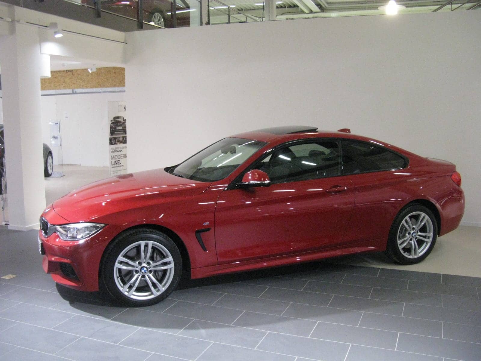 Red BMW 435i M Sport coupé in a showroom, side view