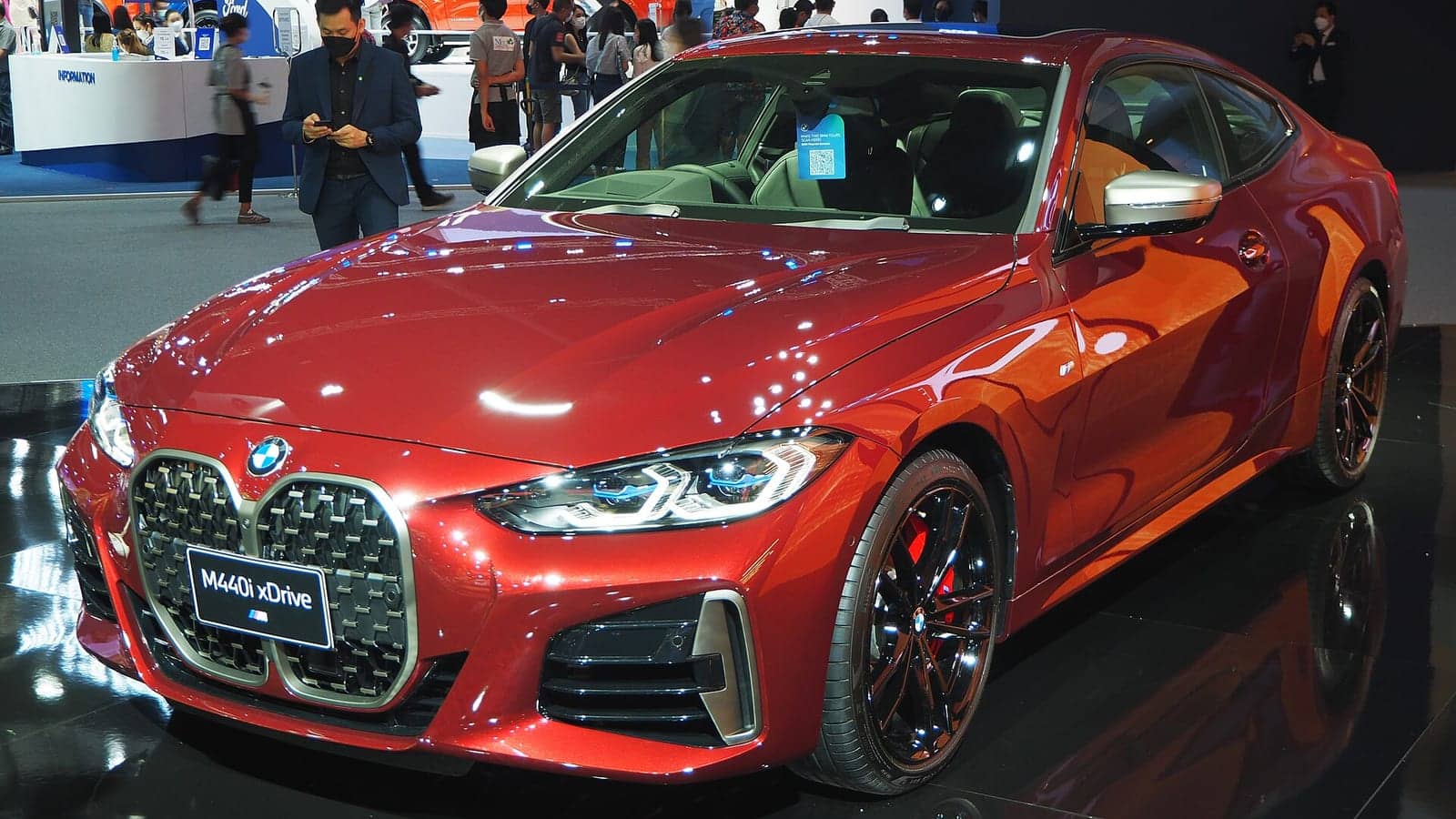 Red BMW M440i xDrive coupé at a motor show, front three-quarter view