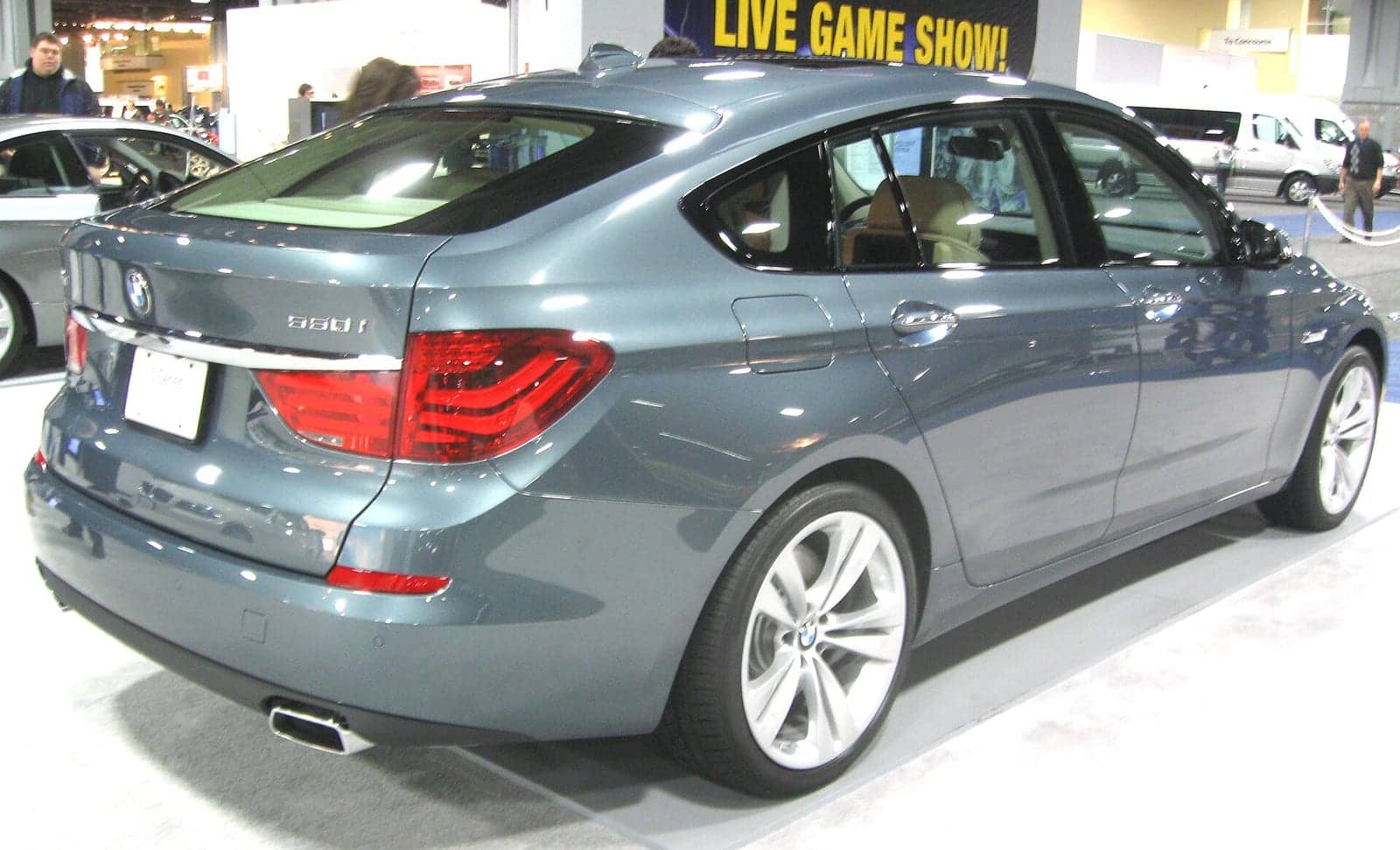 Grey BMW 550i Gran Turismo at a motor show, rear three-quarter view
