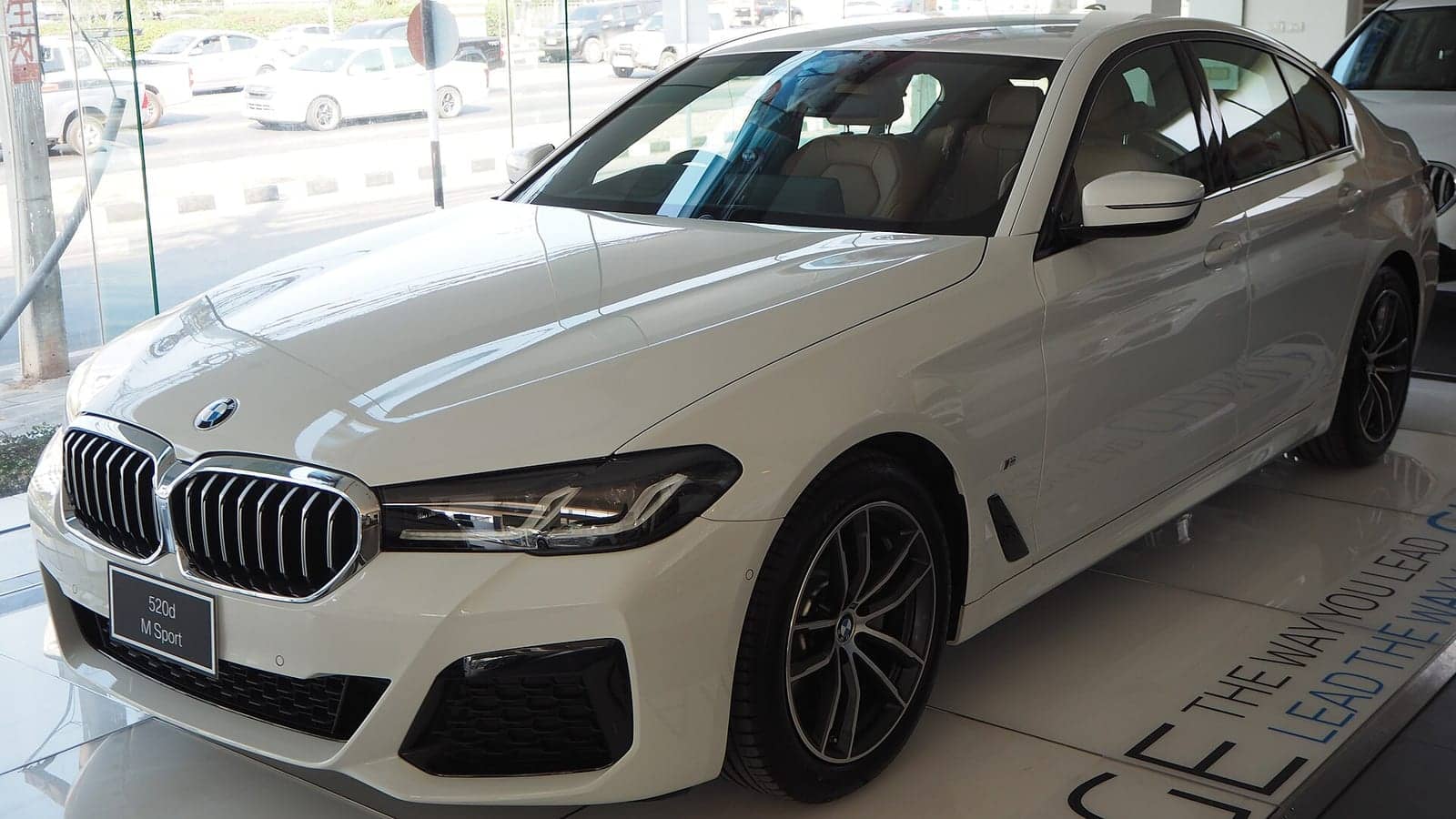 White BMW 520d M Sport in a showroom, front three-quarter view
