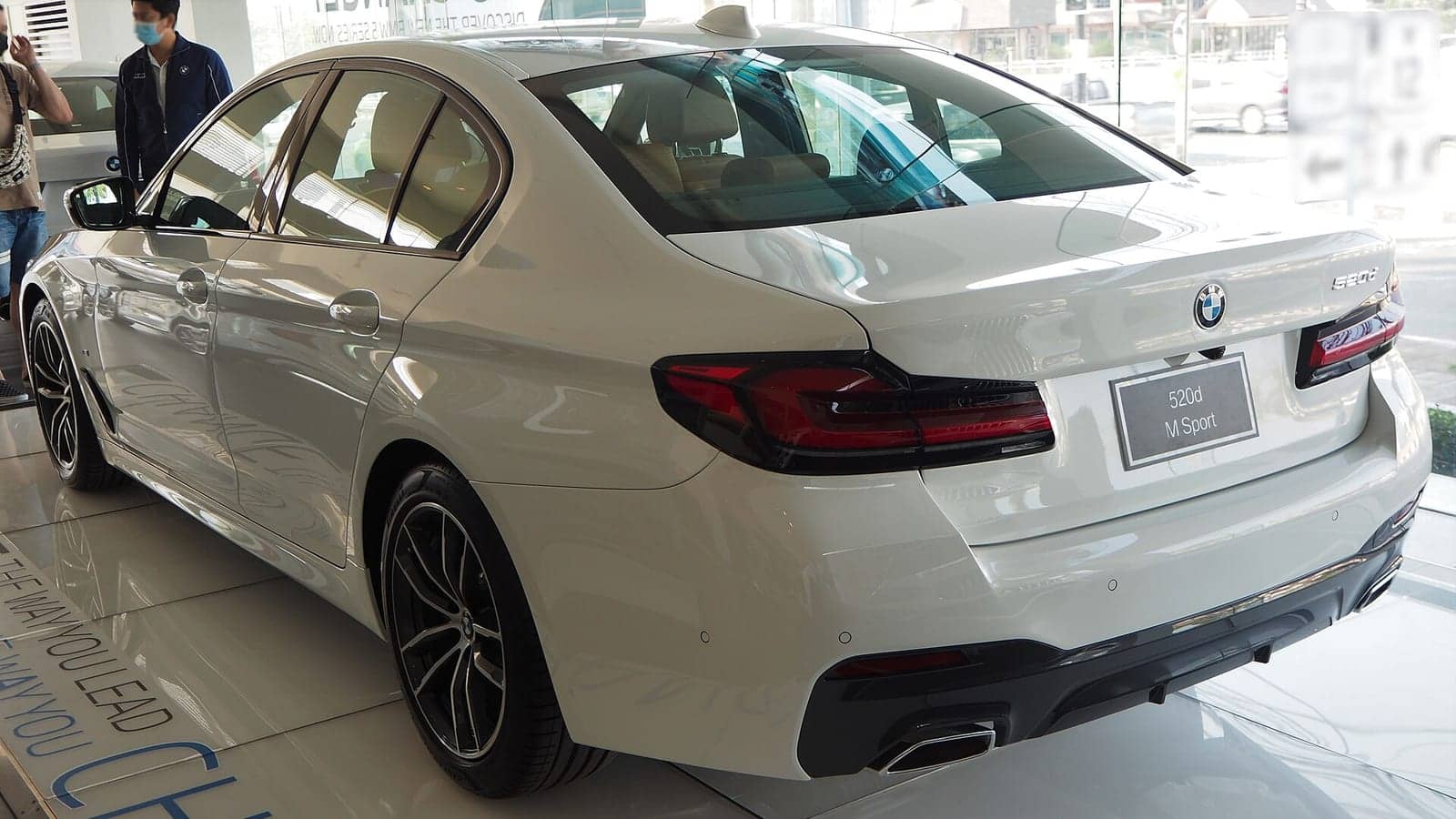 White BMW 520d M Sport in a showroom, rear three-quarter view