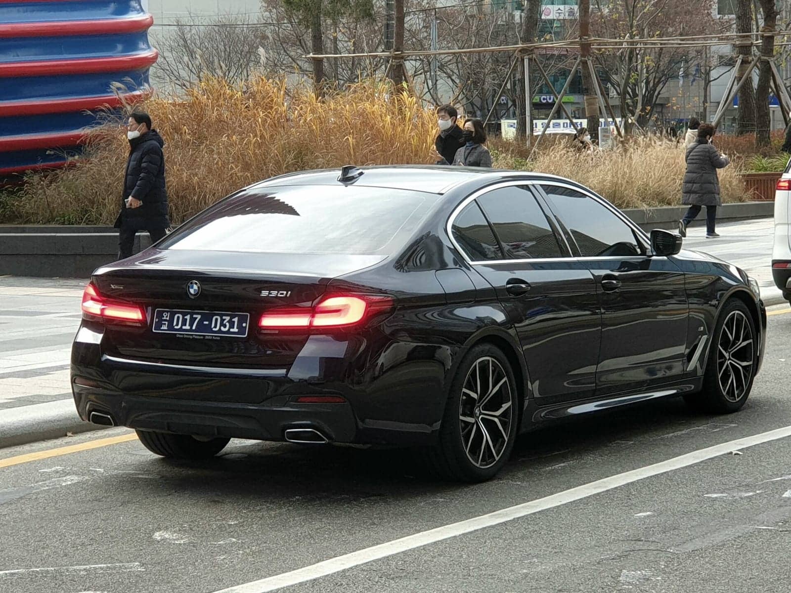 Black BMW 530i, rear three-quarter view