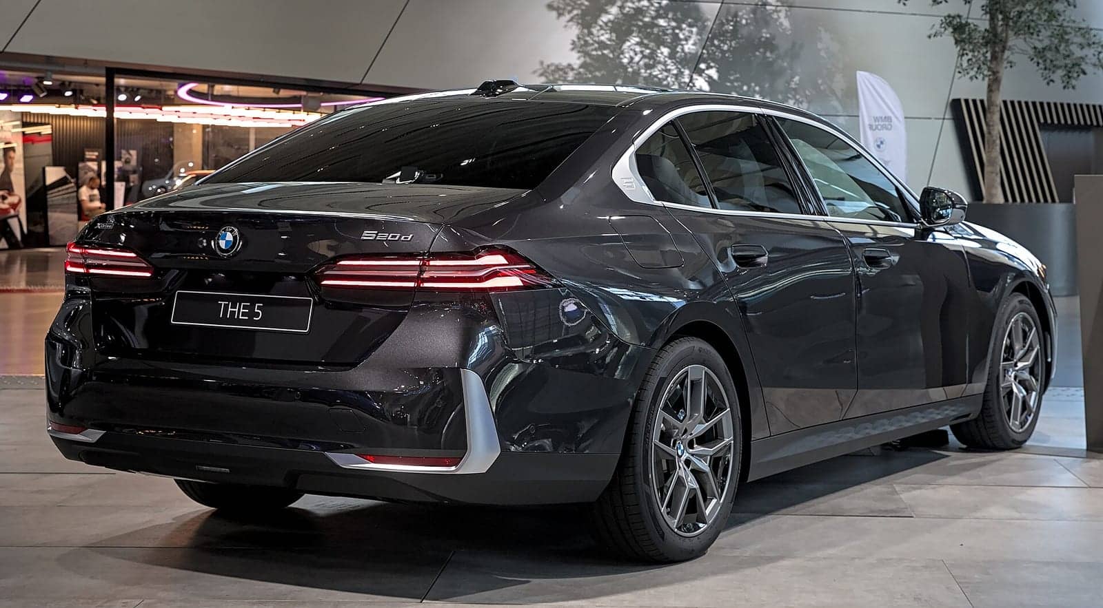 Black BMW 520d at a motor show, rear three-quarter view