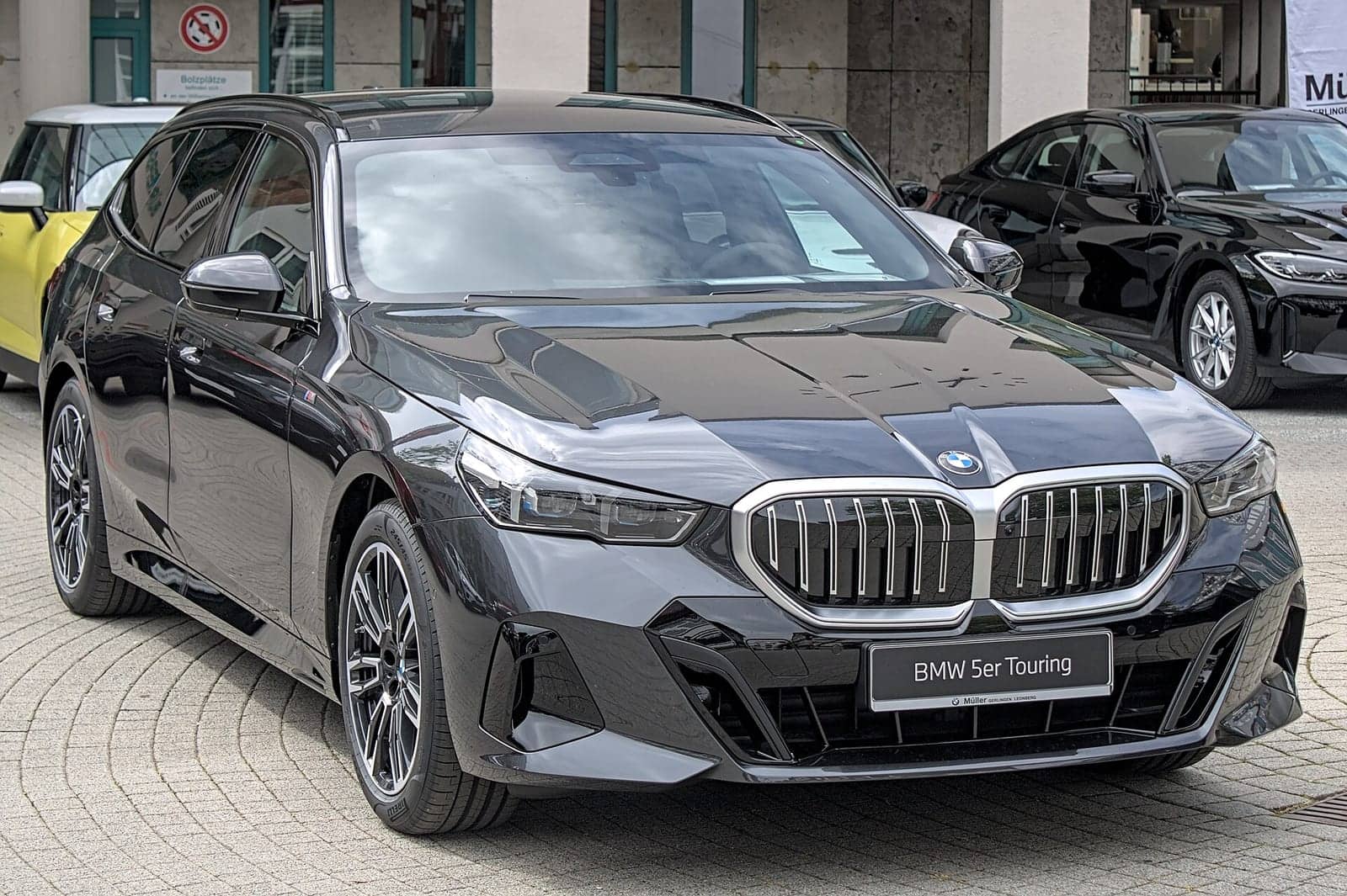 Black BMW 520d Touring in a showroom, front three-quarter view