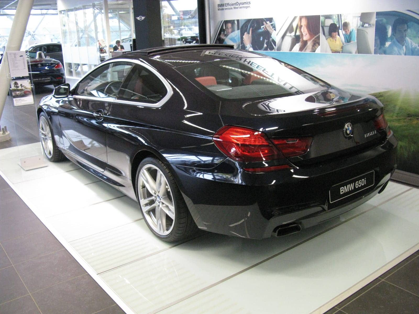 Black BMW 650i coupé in a showroom, rear three-quarter view