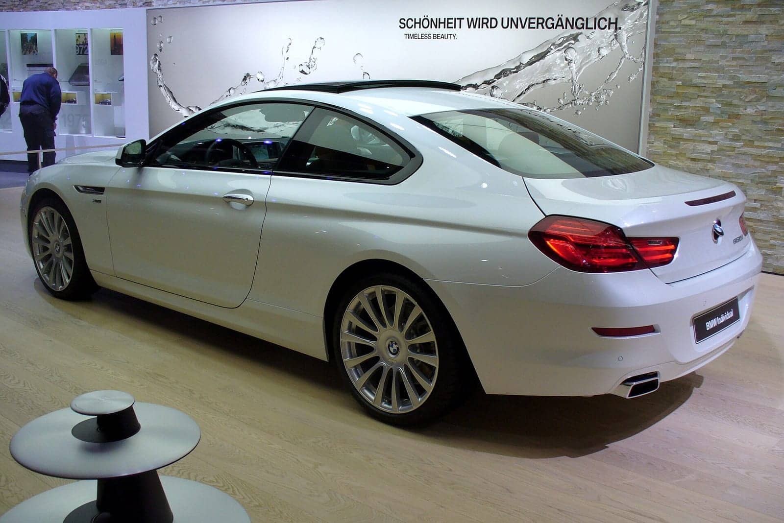 White BMW 650i xDrive Individual coupé at a motor show, rear three-quarter view